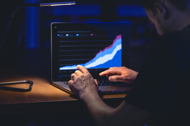 Man trading, browsing online stock investments at night.